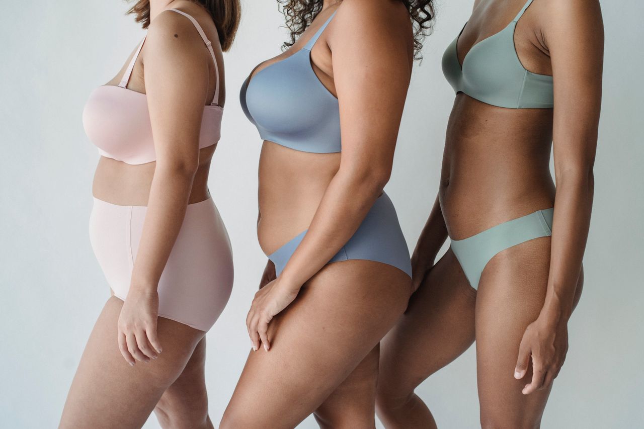Diverse group of women modeling pastel-colored lingerie on a white background.